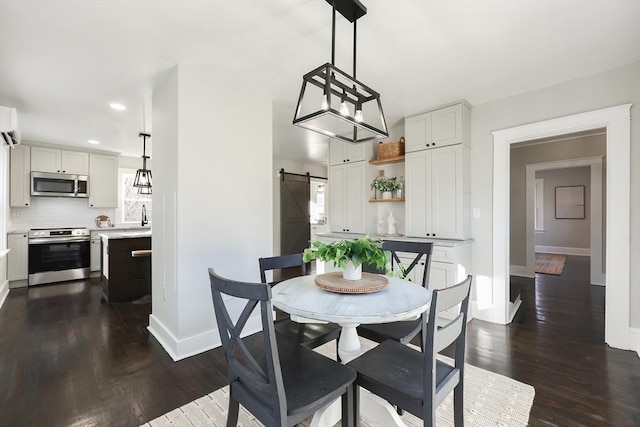 dining area with a barn door, an AC wall unit, dark wood-type flooring, and sink