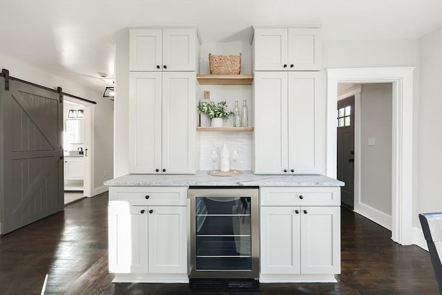 bar with a barn door, dark hardwood / wood-style flooring, white cabinets, and beverage cooler