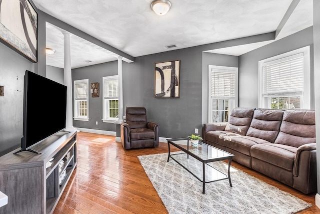 living room featuring baseboards, ornate columns, visible vents, and plenty of natural light