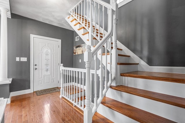 foyer entrance with stairway, hardwood / wood-style flooring, baseboards, and visible vents