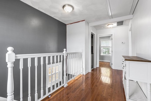 corridor with hardwood / wood-style flooring, baseboards, an upstairs landing, and visible vents