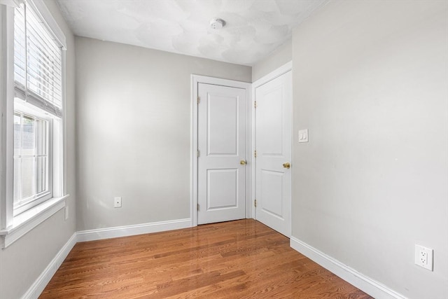 unfurnished room with light wood-type flooring and baseboards