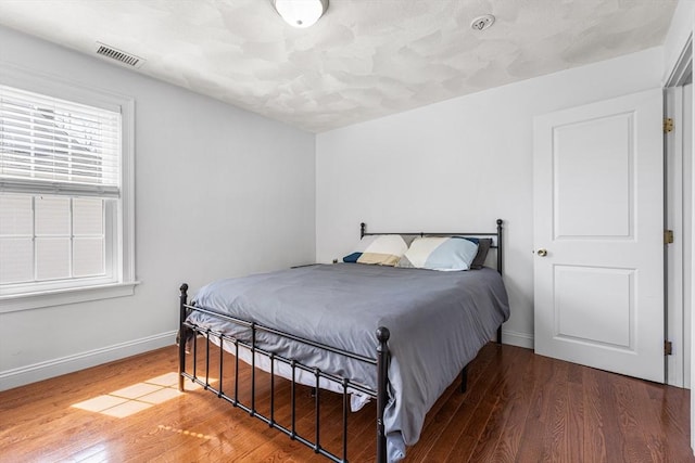 bedroom featuring multiple windows, visible vents, and wood finished floors