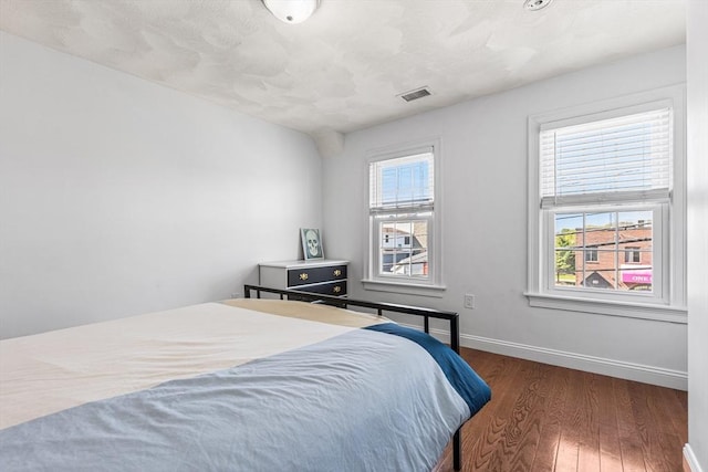 bedroom featuring baseboards, visible vents, and wood finished floors