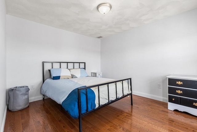 bedroom with wood finished floors, visible vents, and baseboards