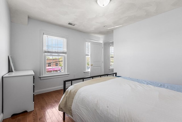 bedroom with visible vents, wood finished floors, and baseboards