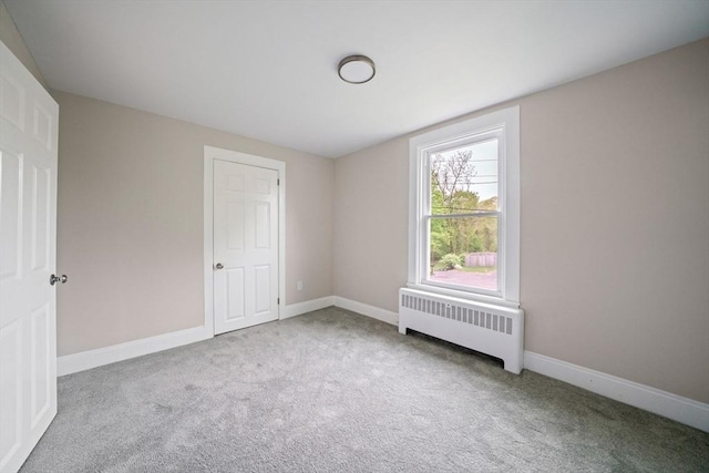 unfurnished bedroom with radiator, carpet, and baseboards