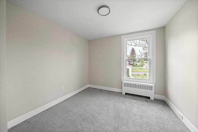 spare room featuring radiator heating unit, carpet flooring, and baseboards