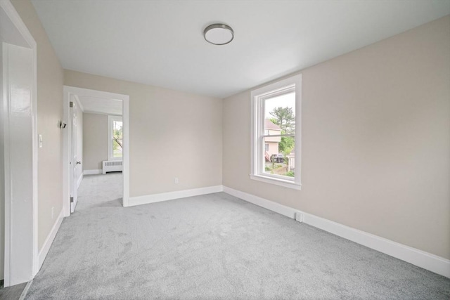 unfurnished room with carpet floors, radiator, and baseboards
