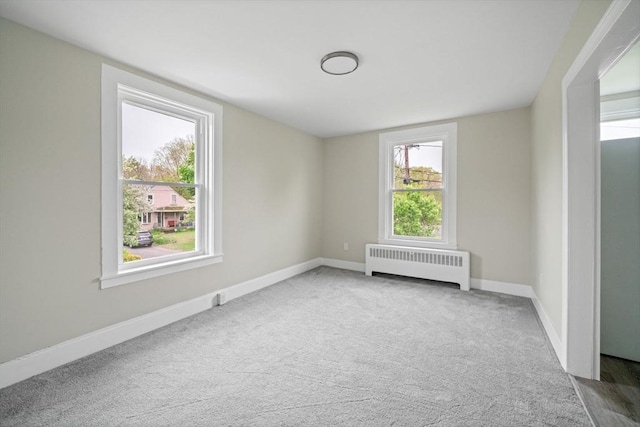 carpeted spare room with radiator heating unit and baseboards