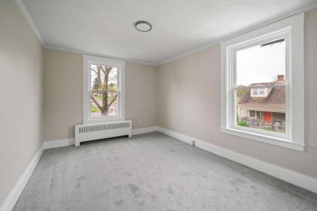 carpeted empty room with radiator, ornamental molding, and baseboards