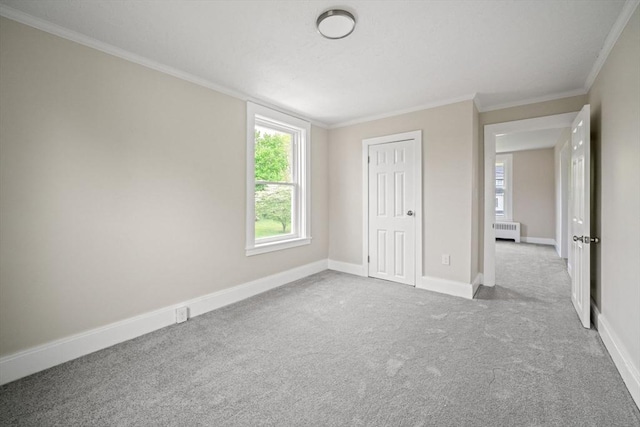 unfurnished bedroom with radiator, carpet flooring, crown molding, baseboards, and a closet