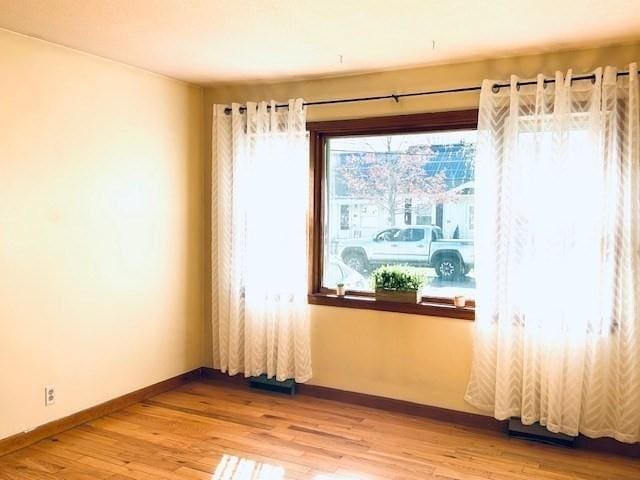 unfurnished room featuring baseboards and light wood-type flooring