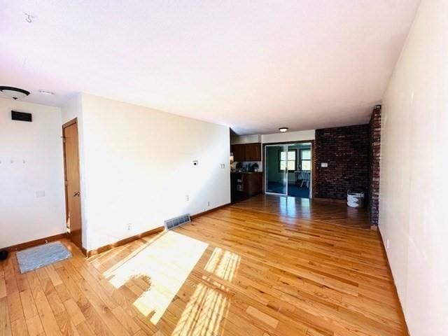 unfurnished living room featuring baseboards, visible vents, and light wood finished floors