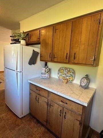 kitchen featuring light countertops, brown cabinets, and freestanding refrigerator