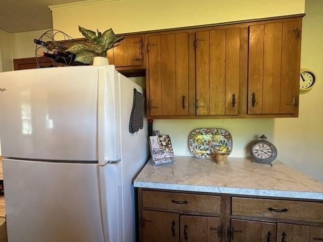 kitchen featuring freestanding refrigerator, brown cabinets, and light countertops