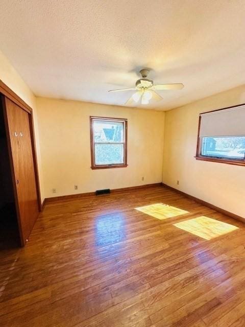 empty room featuring baseboards, a wealth of natural light, and wood finished floors