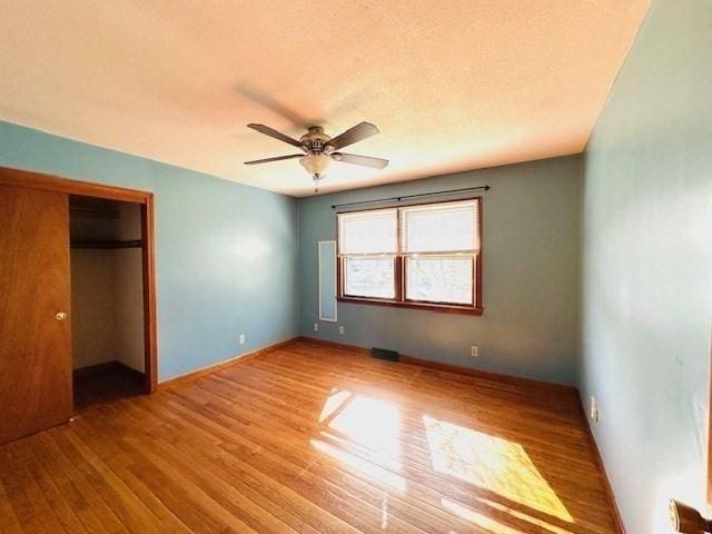 unfurnished bedroom with baseboards, ceiling fan, wood finished floors, and a closet