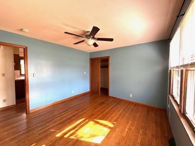 unfurnished room featuring plenty of natural light, baseboards, ceiling fan, and wood finished floors
