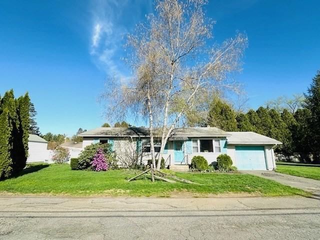 ranch-style home with an attached garage, driveway, and a front lawn