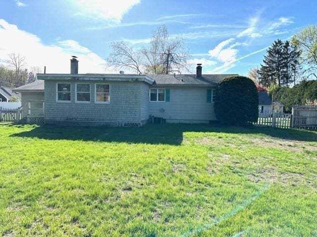 back of house featuring fence, a chimney, and a yard