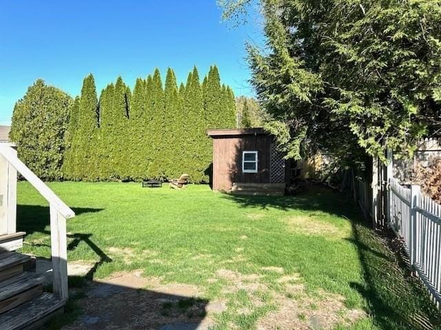 view of yard with an outdoor structure, a storage shed, and a fenced backyard