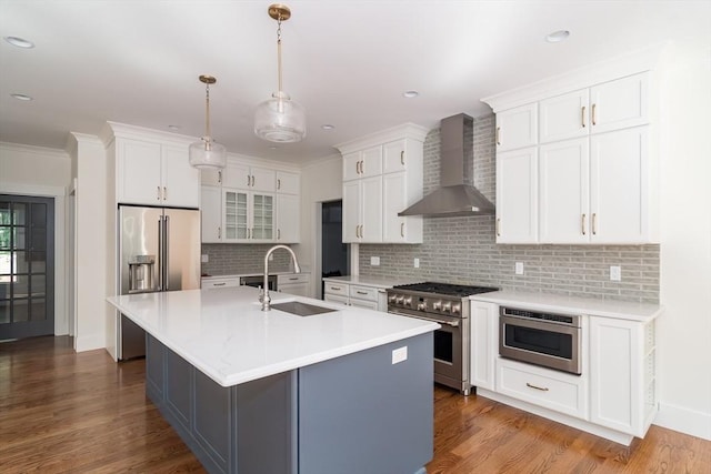 kitchen with white cabinets, high quality appliances, sink, and wall chimney exhaust hood