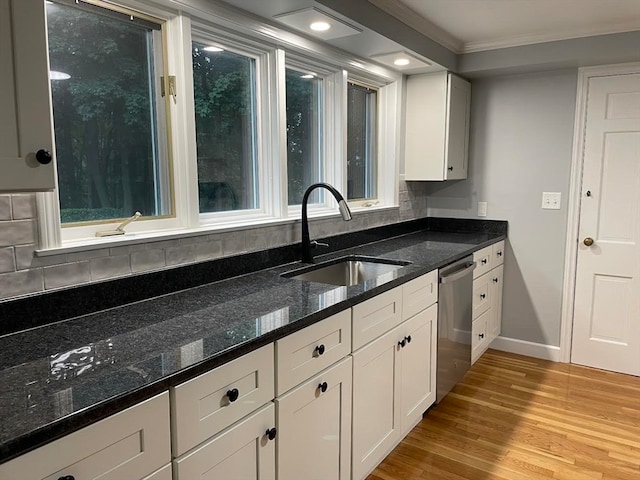 kitchen with dark stone counters, white cabinetry, sink, and stainless steel dishwasher