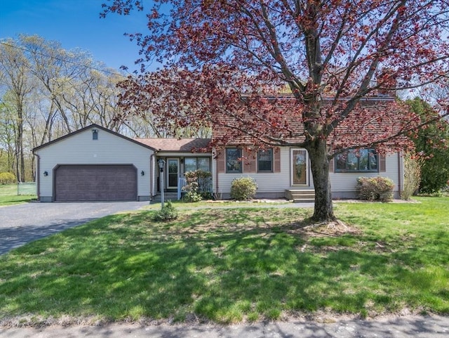 view of front of home with an attached garage, driveway, a front lawn, and entry steps