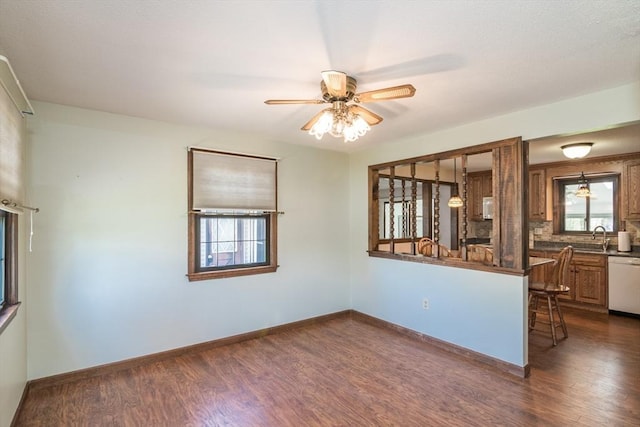 interior space with a sink, dark countertops, white dishwasher, and dark wood-type flooring