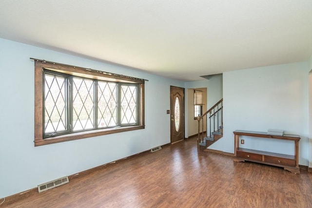 foyer entrance featuring visible vents, wood finished floors, baseboards, and stairs