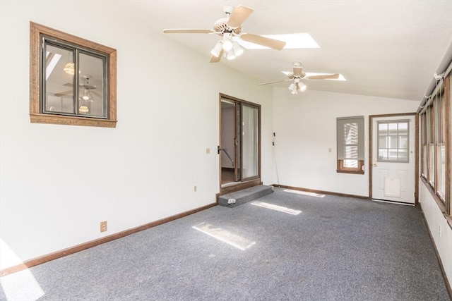spare room featuring ceiling fan, carpet, baseboards, and lofted ceiling with skylight
