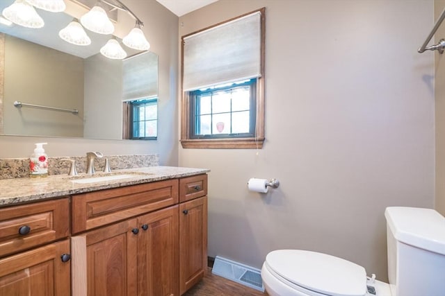 bathroom featuring toilet, wood finished floors, vanity, visible vents, and baseboards