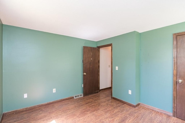 empty room with visible vents, wood finished floors, and baseboards