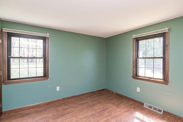 spare room featuring baseboards, visible vents, and wood finished floors