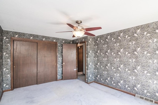 unfurnished bedroom with carpet, a ceiling fan, visible vents, and wallpapered walls