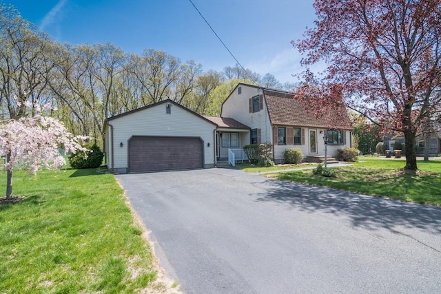 view of front of property featuring a front lawn, a gambrel roof, aphalt driveway, and an attached garage