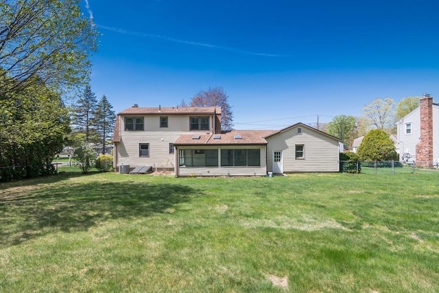 back of property featuring a lawn, central AC, and fence