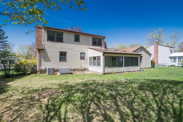rear view of property featuring cooling unit, a sunroom, a yard, and fence