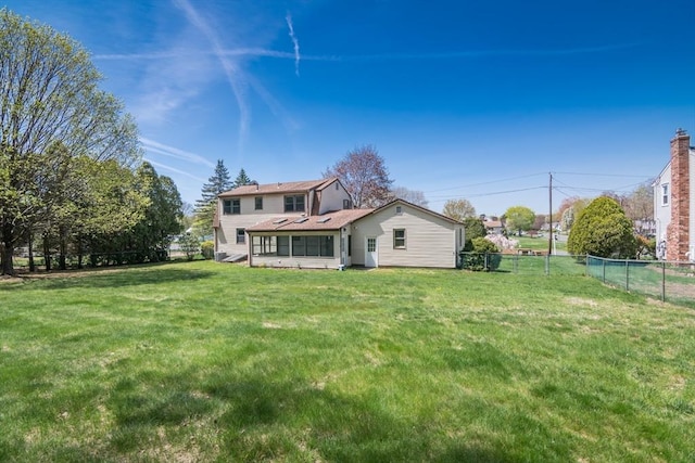 back of property featuring a sunroom, a yard, and fence