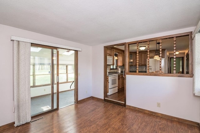 spare room featuring baseboards, a textured ceiling, and dark wood-style floors