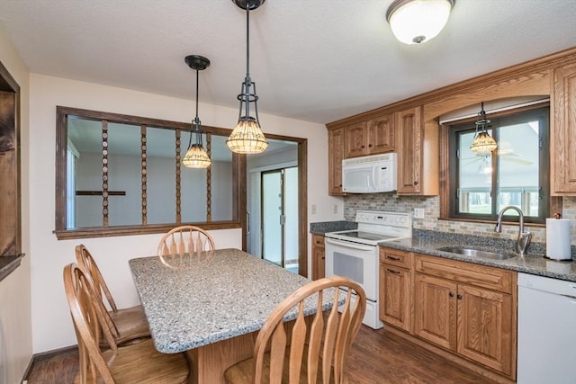kitchen with a sink, white appliances, a kitchen bar, and dark wood-type flooring