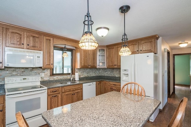 kitchen featuring a center island, a sink, brown cabinetry, white appliances, and tasteful backsplash