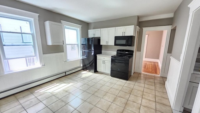 97-99 Blaisdell St Unit 2, Haverhill, MA 01832 - kitchen with black appliances, a baseboard radiator, white cabinets, wainscoting, and light countertops