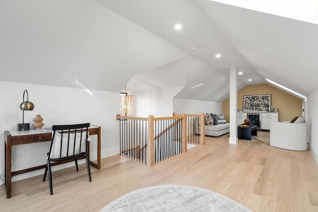 additional living space featuring wine cooler, light wood-type flooring, and vaulted ceiling