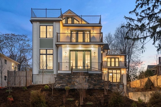 back house at dusk featuring a balcony