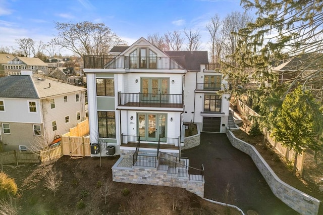 rear view of house with french doors, central AC unit, a garage, and a balcony