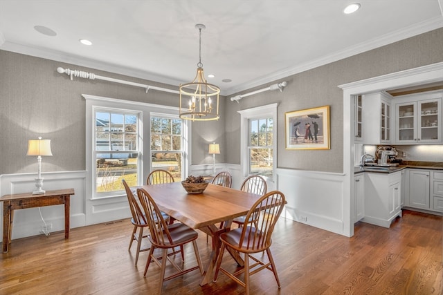 dining space with a notable chandelier, ornamental molding, and wood-type flooring