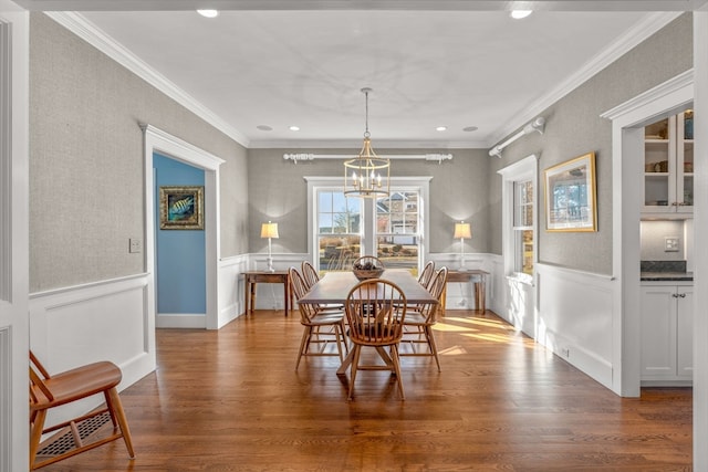 dining space with ornamental molding, an inviting chandelier, and hardwood / wood-style floors