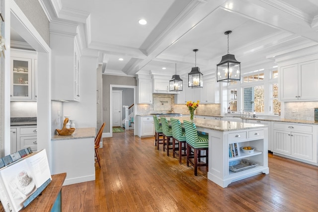 kitchen featuring a center island, decorative backsplash, hardwood / wood-style flooring, and coffered ceiling